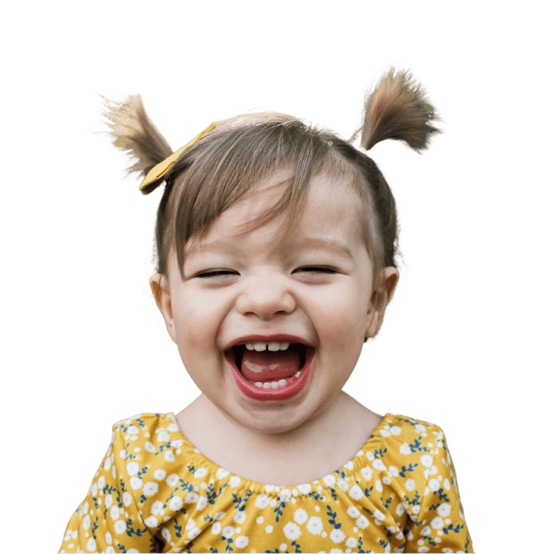 A young child with pigtails and a yellow floral dress smiles widely with their mouth open, against a plain white background.